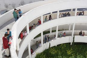 Several students talking in hallways of a building that has three outdoor stories.