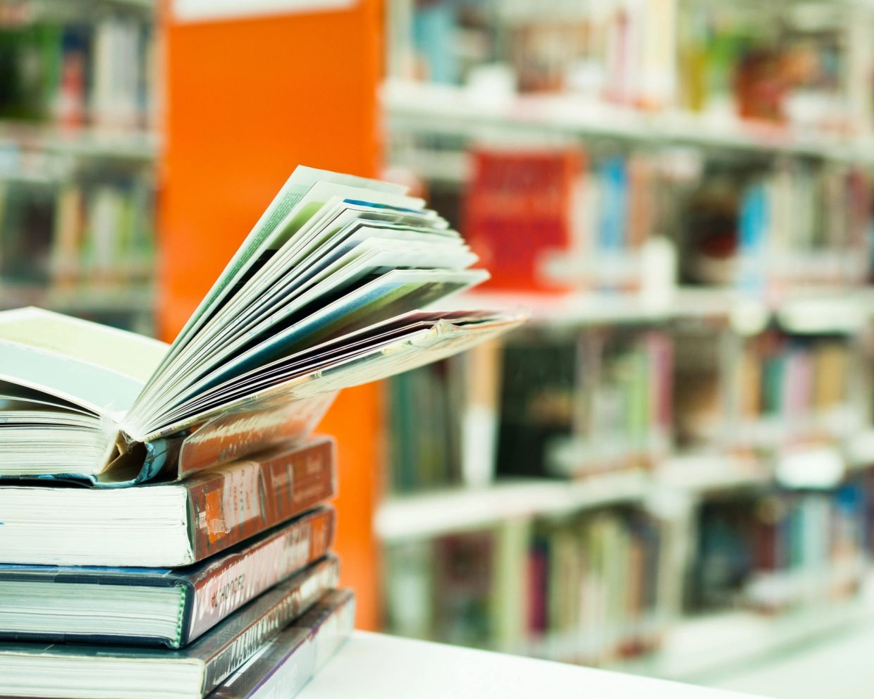 An open book on top of closed books.