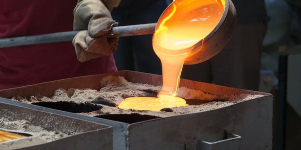 Molten metal being poured into a sand mold for casting.