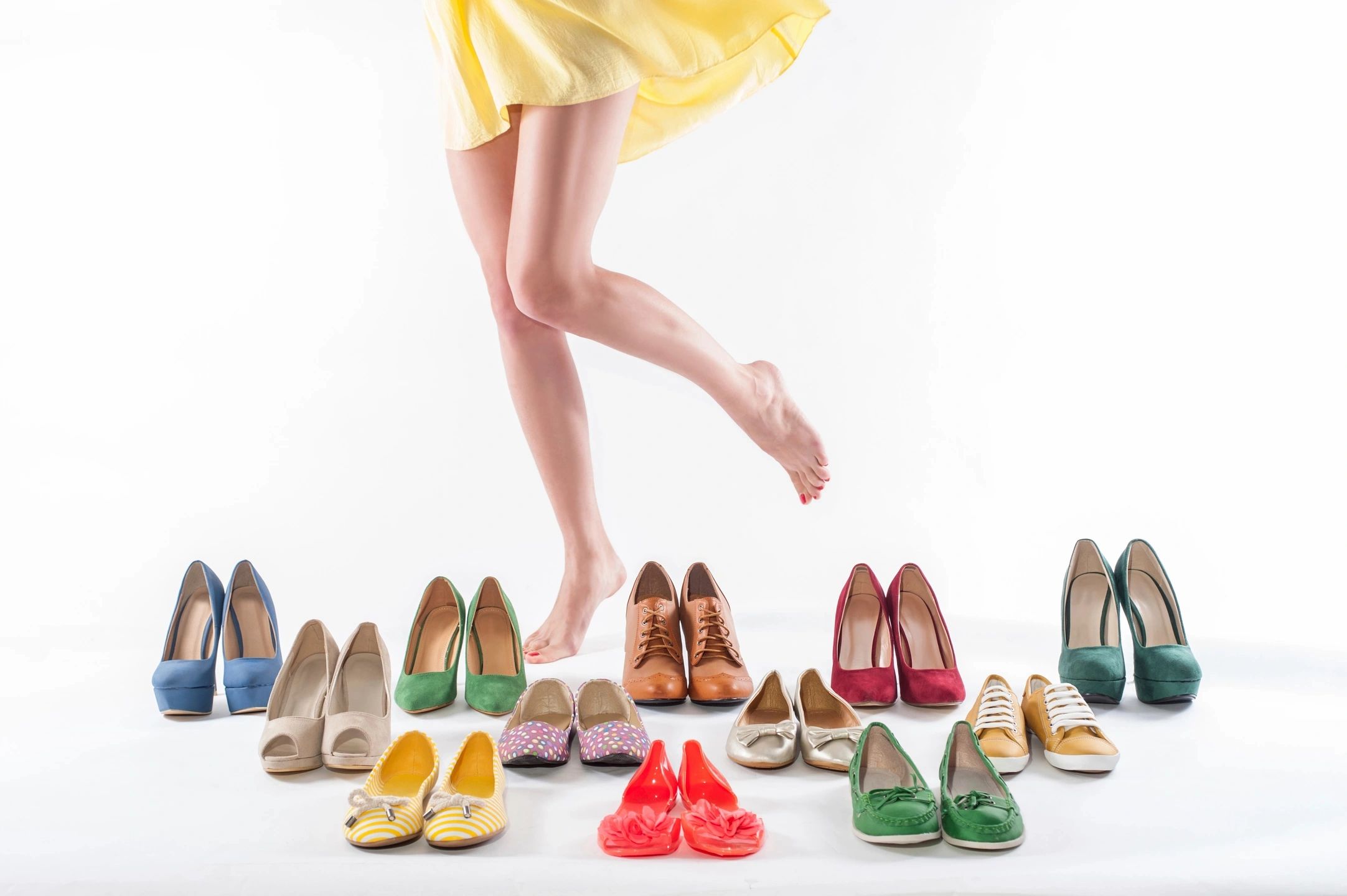Woman in yellow dress choosing from a colorful shoe collection.