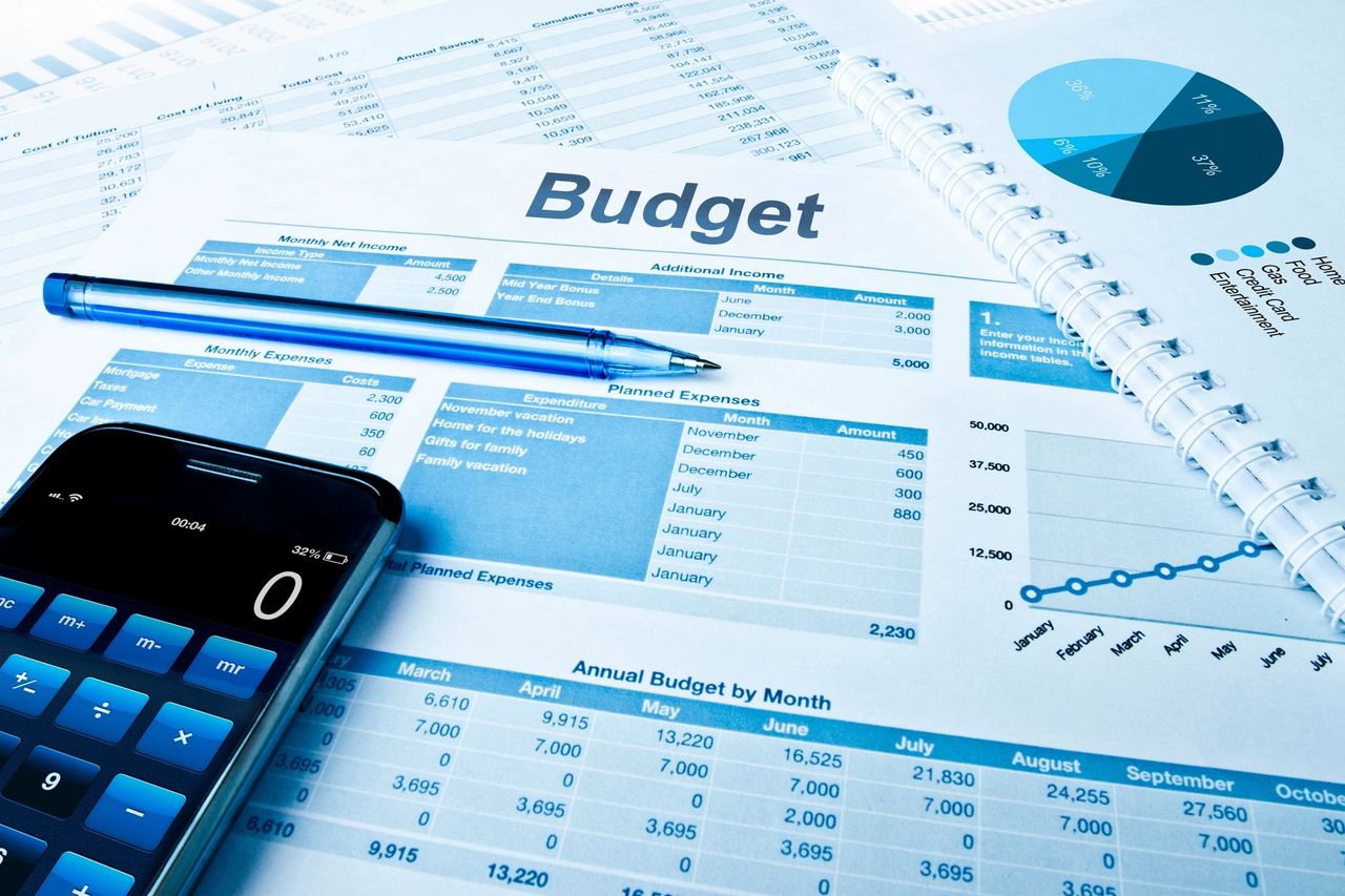 Paperwork, calculator and a pen lay on a desk as a buyer reviews their budget in preparation for purchasing a new home.