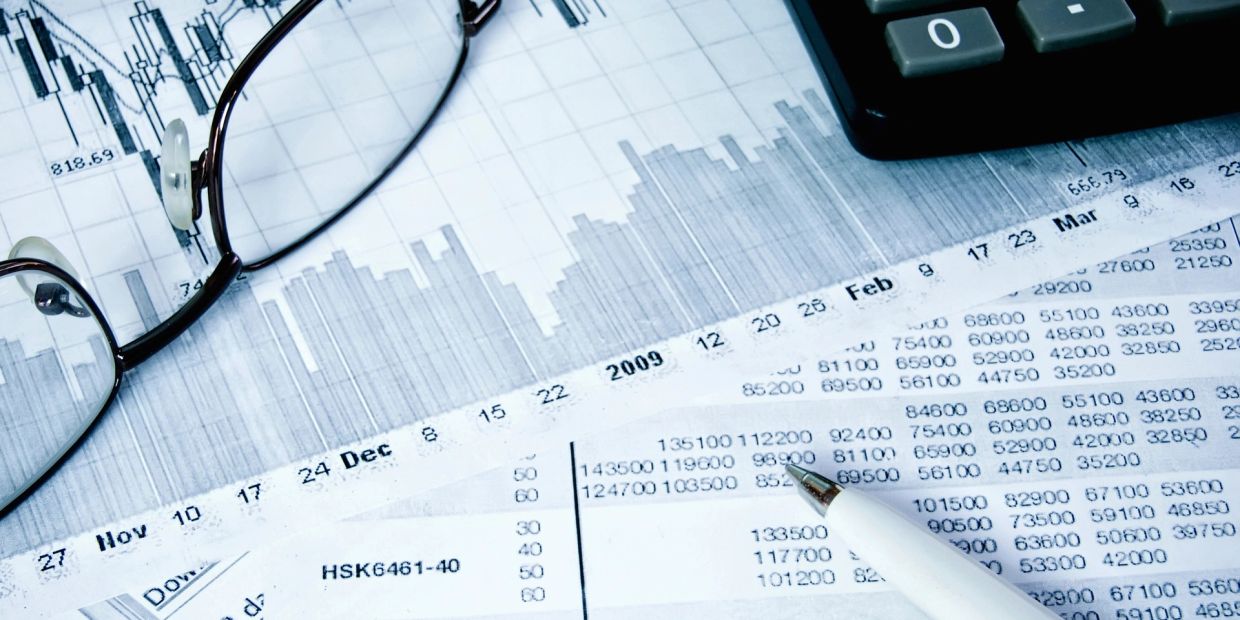 Financial documents with charts, glasses, and a pen.