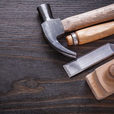 Beautiful dark stained wood with a hammer, chisels and a hand planer laying on top.