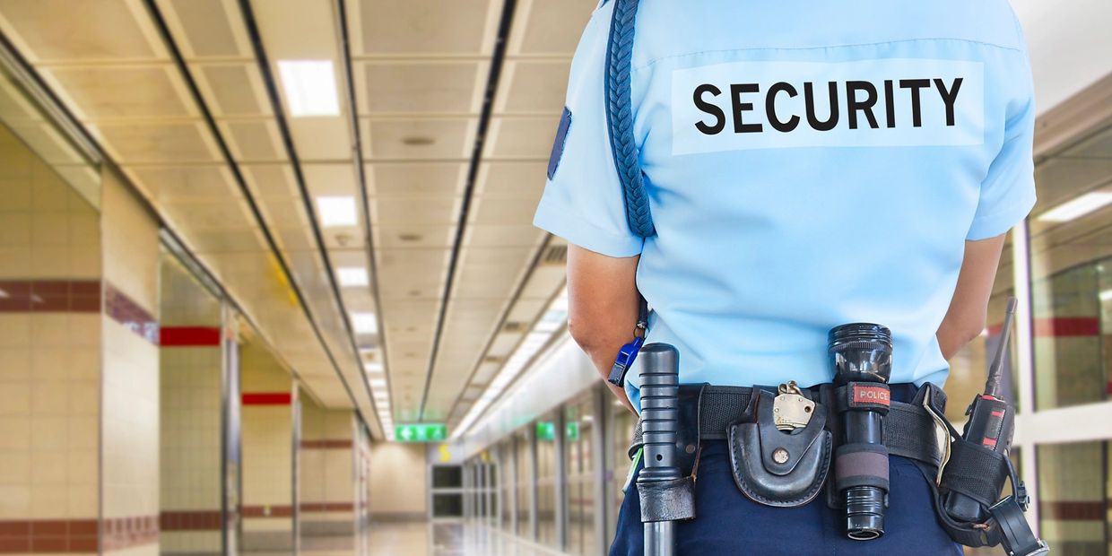 Security guard standing in a hallway with equipment on belt.