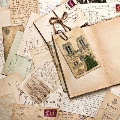 Vintage letters and postcards with handwritten notes and illustrations spread out on a surface.