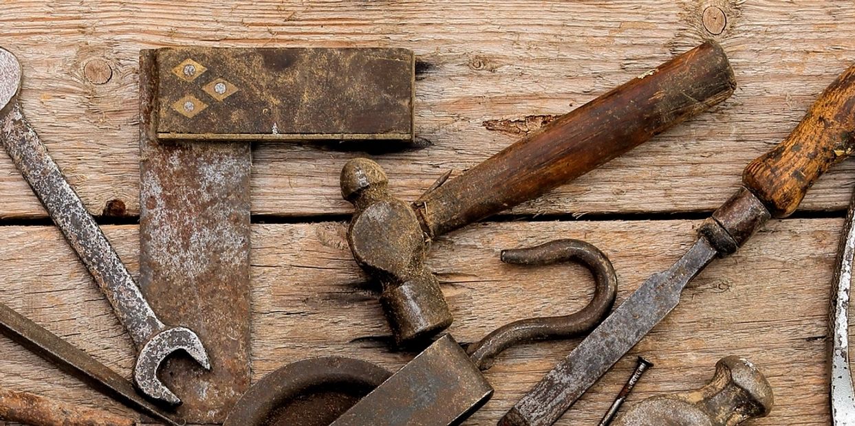 Old rusty hand tools on wooden surface.