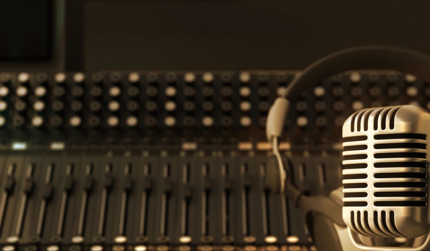 Vintage microphone and headphones in a recording studio with mixing console.