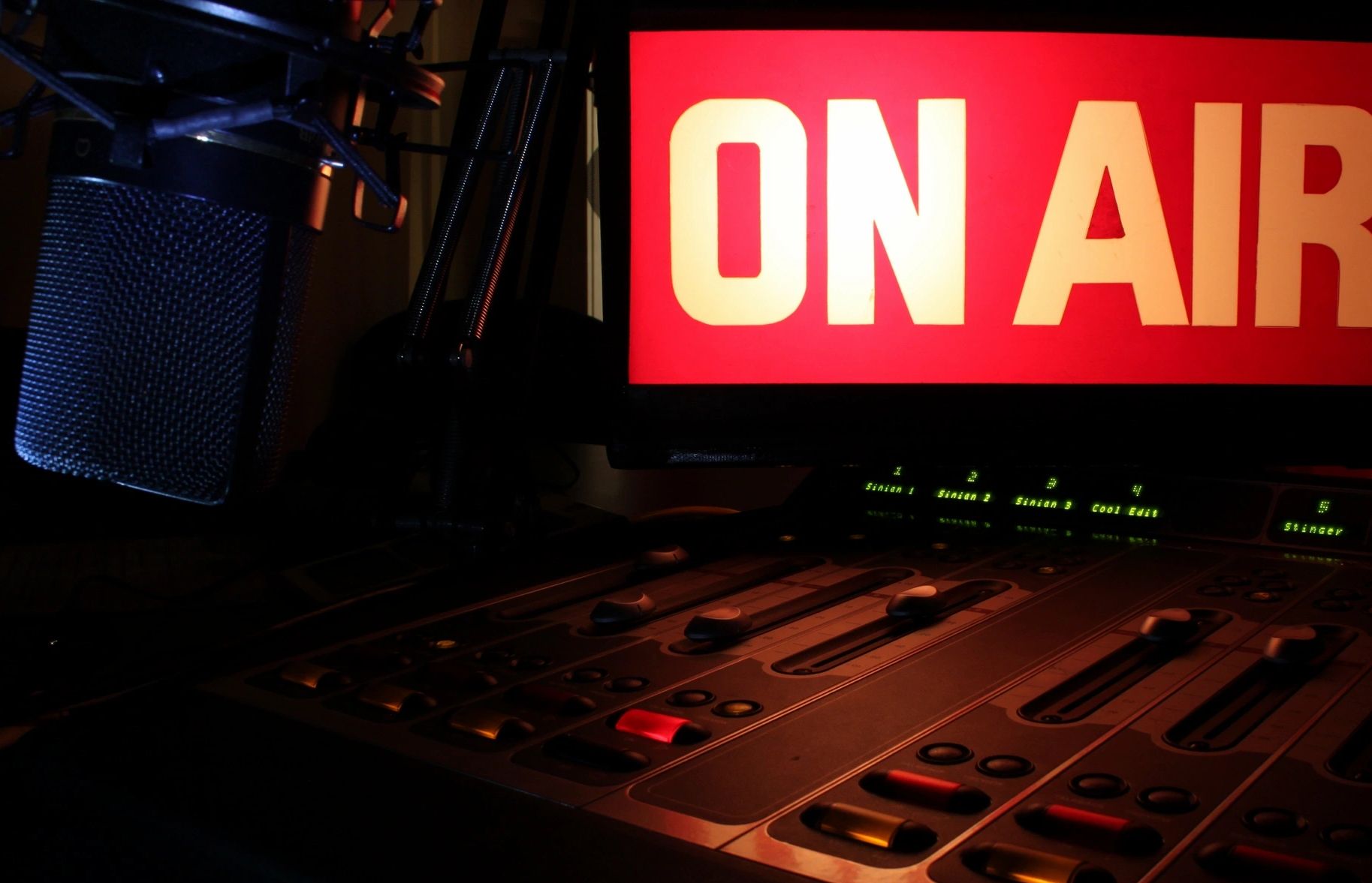 Radio studio setup with a microphone and an illuminated 'ON AIR' sign.