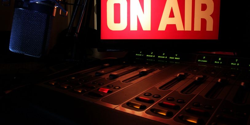 Radio studio control panel with 'ON AIR' sign lit up.