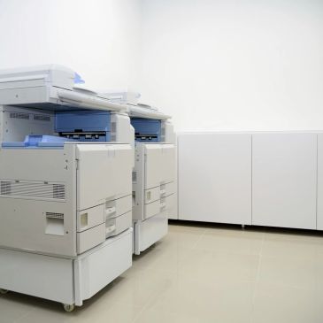 Two large office photocopiers in a clean room.