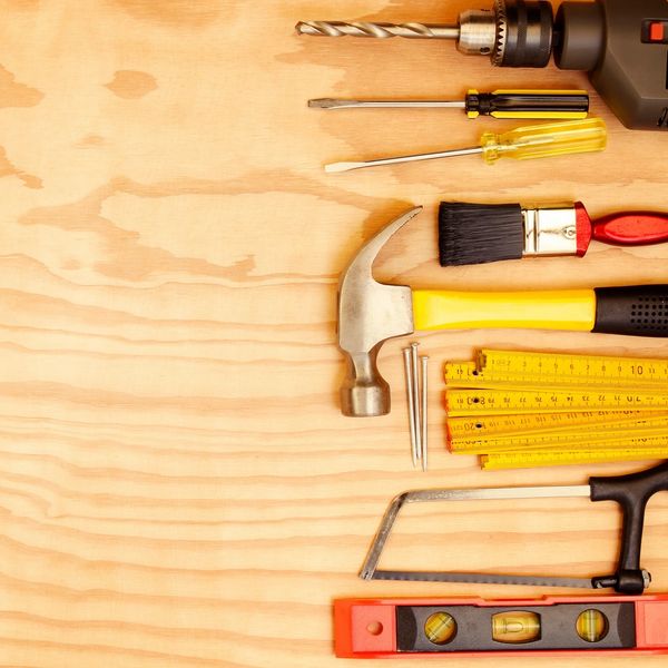 A set of various hand tools arranged on a wooden surface.