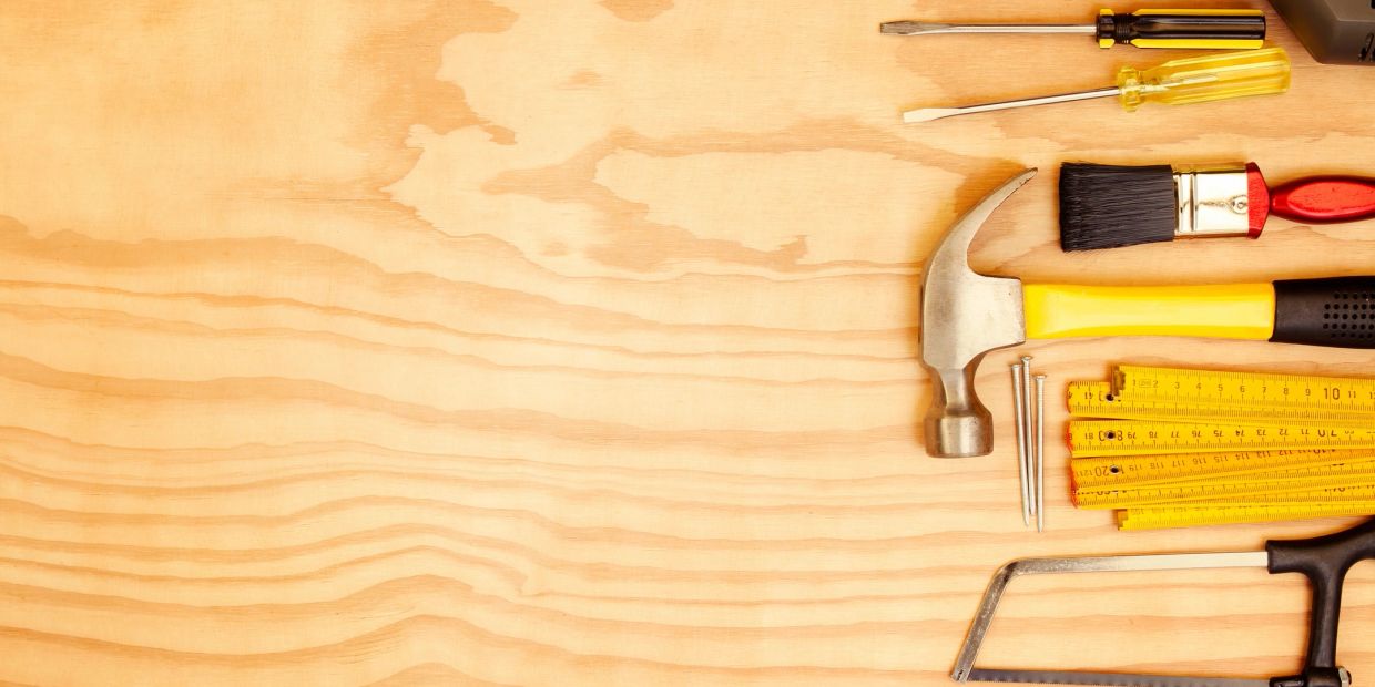 Various hand tools arranged on a wooden surface.