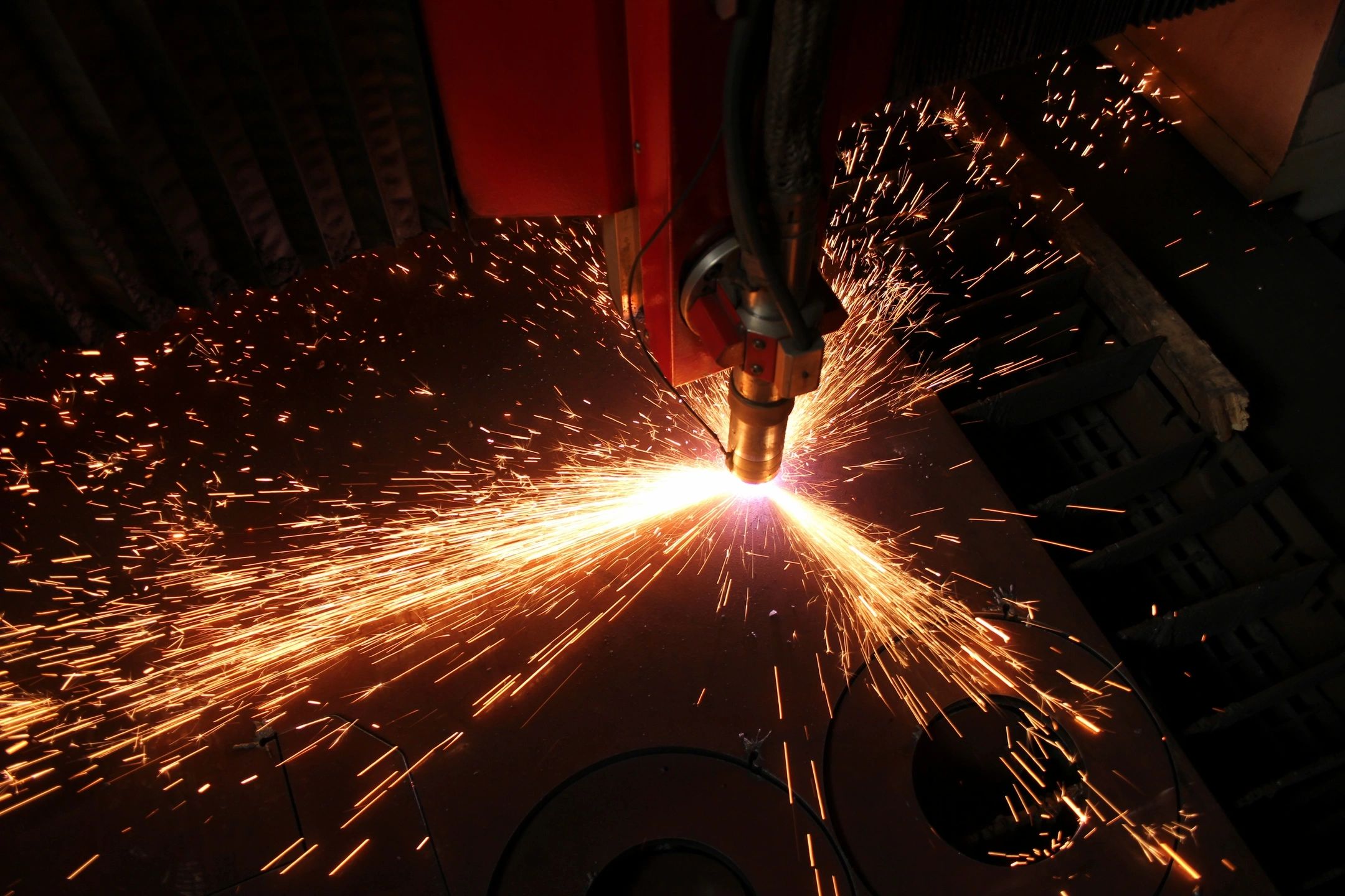 Bright sparks fly as a machine cuts through metal in a workshop.