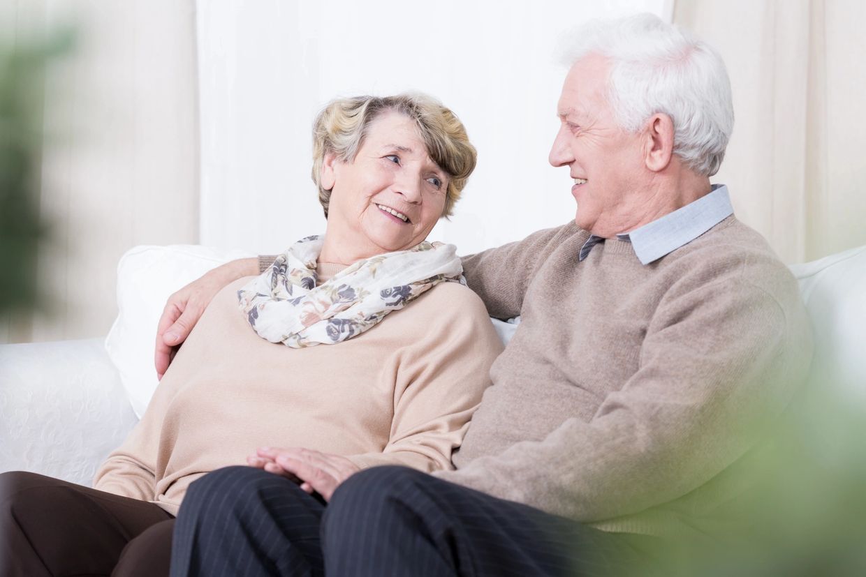 Elderly couple sharing a loving moment on the couch.