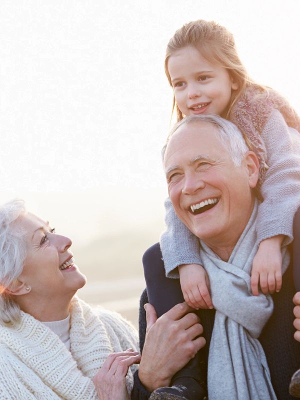 Happy grandparents with their granddaughter outdoors, sharing a joyful moment.