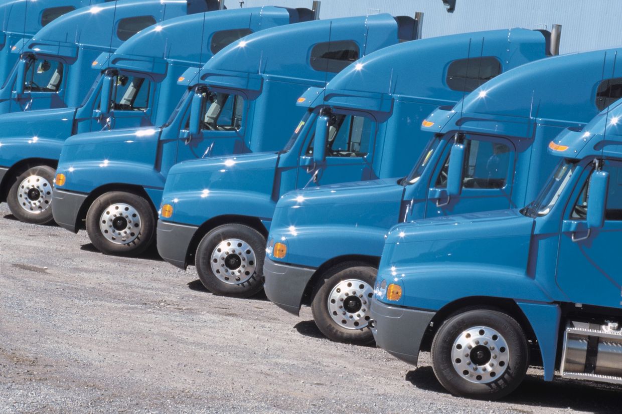 Fleet of blue colored semi-trucks parked in a row.