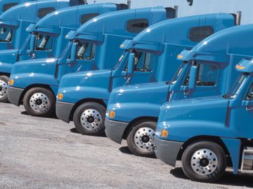fleet of blue semis parked in parking lot