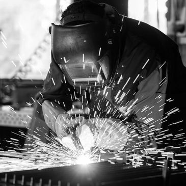 Welder in protective gear creating bright sparks while working.