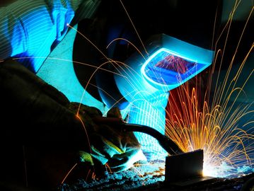 Worker welding metal with sparks flying.