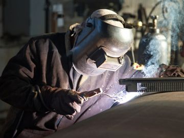 Welder repairing a piece of industrial equipment