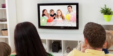 Family watching TV with children on screen.