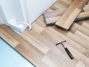 Wooden laminate floor installation in progress with a hammer.