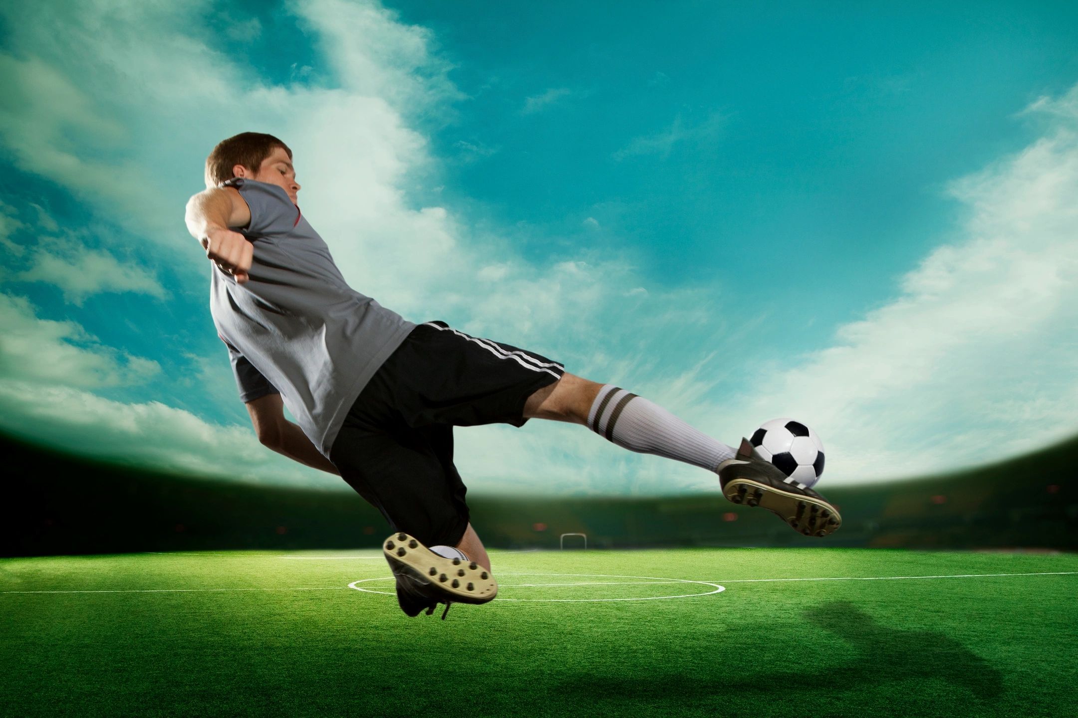 Спортсмен занимающийся футболом. Футболист пинает мяч. Футболист с мячом. Футбольный мяч в воздухе. Футболист в прыжке.