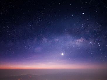 Starry night sky with a glowing horizon and visible Milky Way.