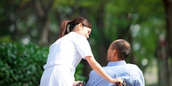 nurse walking man in wheelchair