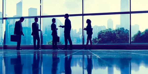 Business professionals discussing in a modern office with city skyline views.