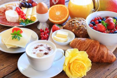 A vibrant breakfast spread with coffee, croissant, fresh fruits, and cheese.