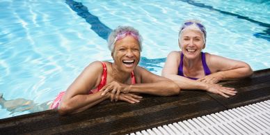 Two elderly women smiling in a swimming pool.