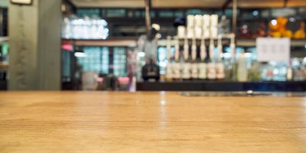 Empty wooden table with blurred bar background.