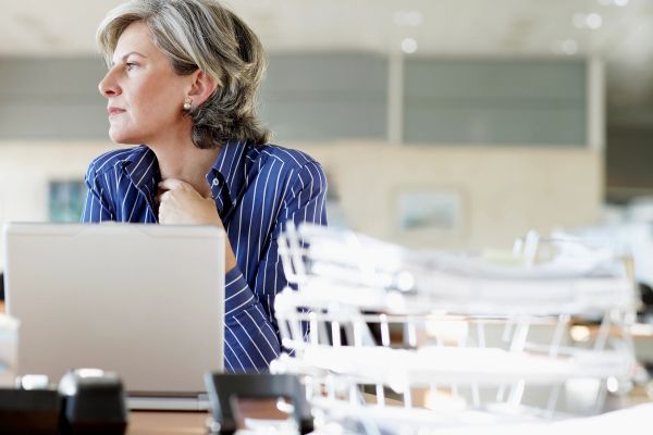 Woman in blue striped shirt looking thoughtfully away from her laptop.