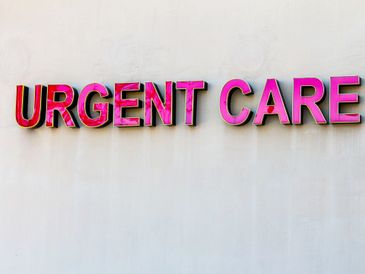 Bright pink 'URGENT CARE' sign on a plain wall.