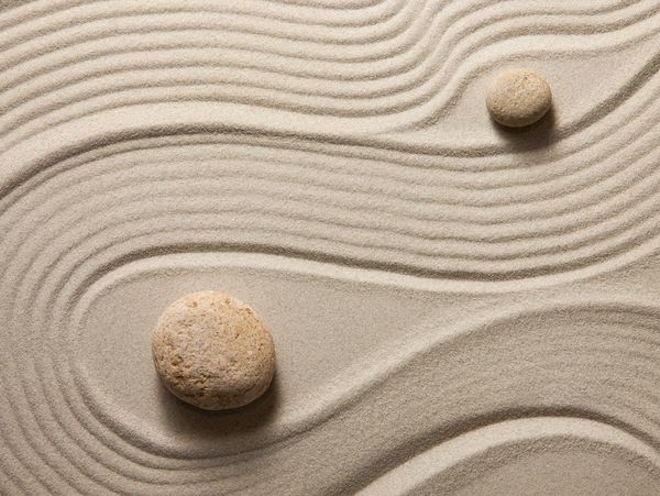 A Zen design  of sand and roocks with a swirl pattern drawn in the sand