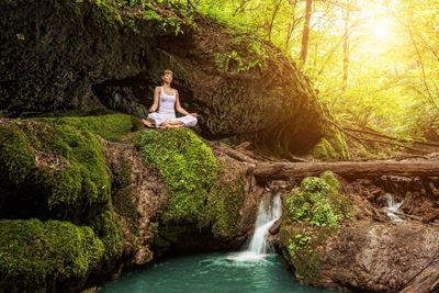 A woman meditation by a small waterfall