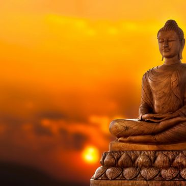 A statue of Buddha with a sunset in the background.