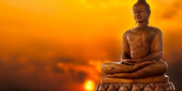 Buddha statue sitting calmly with a sunset in the background