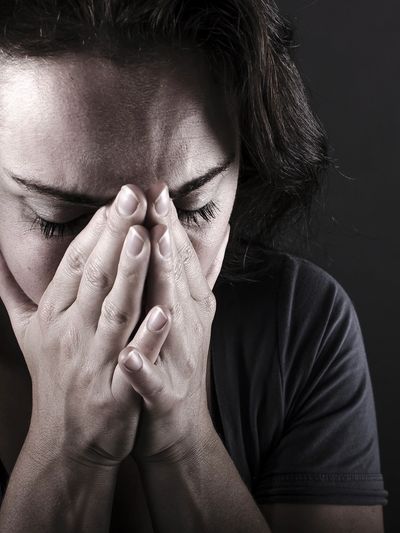 Person covering face with hands, showing distress or sadness.