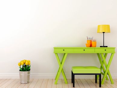 Bright green desk setup with yellow tulips and a lamp in a minimalist room.