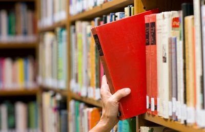 A red book being pulled from a shelf
