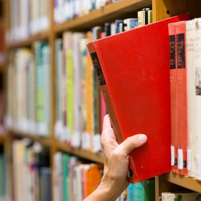 book being taken from library shelf