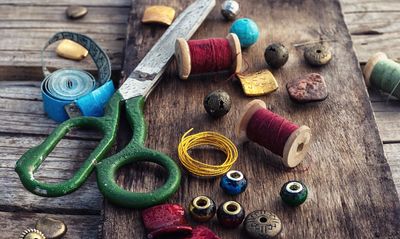 Vintage sewing tools and beads on a wooden surface.