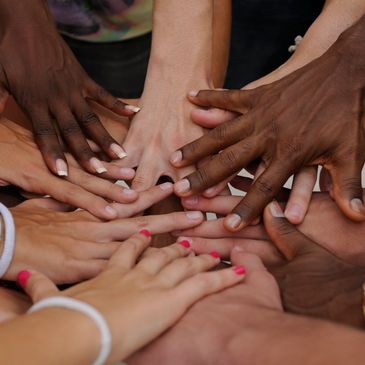 Different hands from diverse backgrounds stacked on each other symbolising unity.