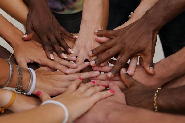 Women's hands reaching toward one another in a circle.
