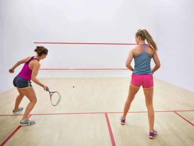 Two women playing squash on an indoor court.