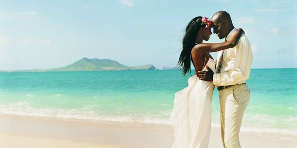 Couple embracing on a beach with turquoise water.