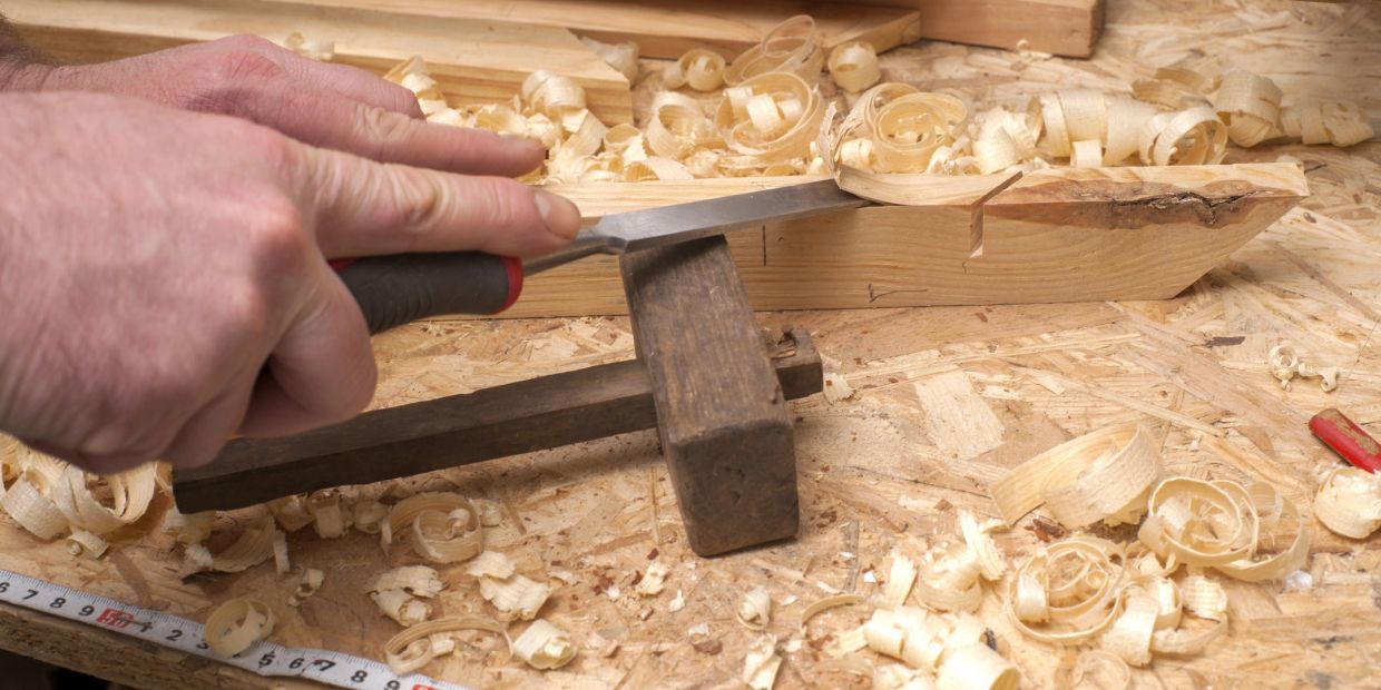 Hand carving wood with a chisel.