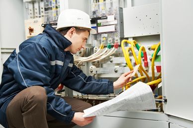 Electrician inspecting wiring with a blueprint.